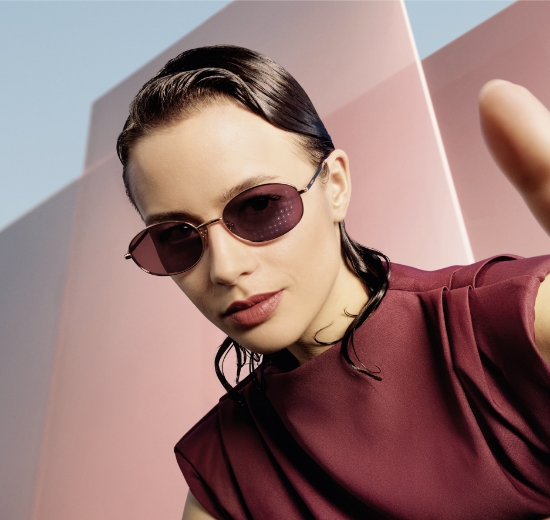 Frau mit Sonnenbrille vor futuristischem Hintergrund. 